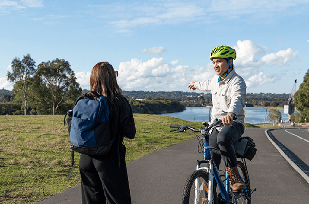 Park ranger with bike helmet and bicycle, interacting with another person, at the Park.