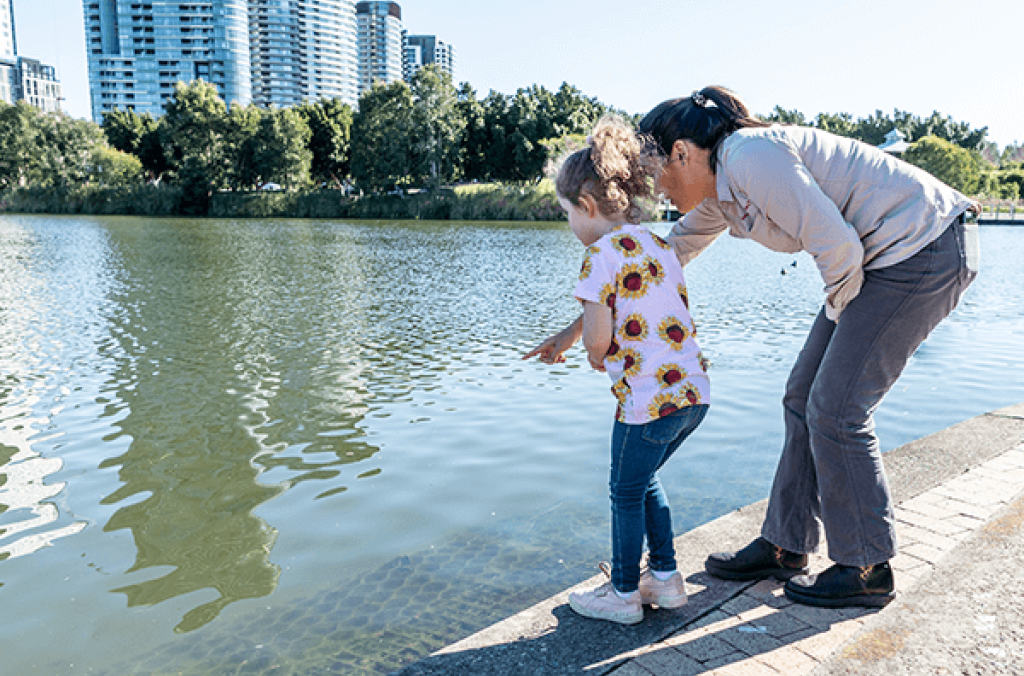 Park ranger interacting with a child by the water in the Park